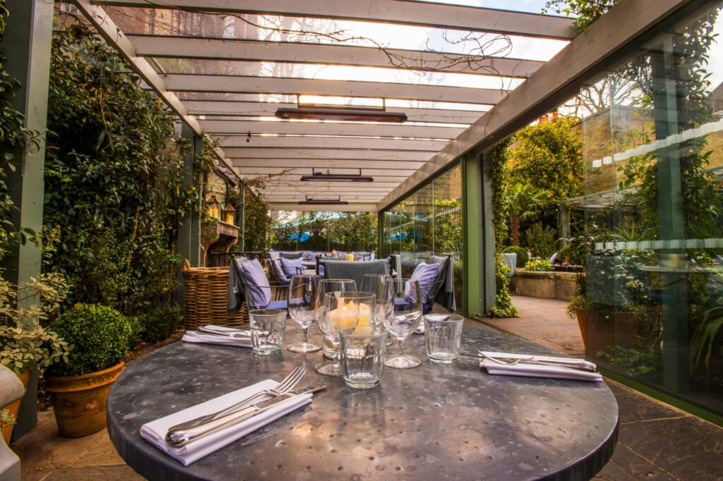 Nahaufnahme eines gedeckten Tisches in einem schönen überdachten Gartenrestaurant mit elektrischen Heizgeräten
